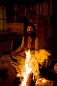 Holy man (sadhu) wearing dreadlocks and covered in ash, beside a fire, during the Hindu festival of Shivaratri, Pashupatinath, Kathmandu, Nepall, Asia