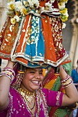 Sari clad woman carrying idol at the Mewar Festival in Udaipur, Rajasthan, India, Asia
