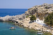 A small white church and fising boats in St. Paul's Bay near Lindos, Rhodes, Dodecanese Islands, Greek Islands, Greece, Europe