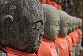 Close up of a row of stone figures wearing red cloth, Sanzen In shrine, Kyoto, Kansai, Honshu, Japan, Asia