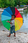 Kleines Mädchen mit großem Schirm in Farben von Regenbogen, Insel Nendo, East New Britain Provinz, Papua-Neuguinea, Südpazifik