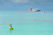 Man paddles kayak off beach at Sandy Beach Resort with expedition cruise ship MS Hanseatic (Hapag-Lloyd Cruises) at anchor behind, Foa Island, Ha'apai Group, Tonga, South Pacific