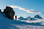 Ein Mensch und ein Zügelpinguin (Pygoscelis antarctica) in schneebedeckter Landschaft, Half Moon Island, Südshetland-Inseln, Antarktis