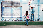 Man points at mural map of Ushuaia as woman looks on, Ushuaia, Tierra del Fuego, Patagonia, Argentina