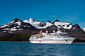 Expedition cruise ship MS Hanseatic (Hapag-Lloyd Cruises) and snow-covered mountain backdrop, Prion Island, near South Georgia Island, Antarctica