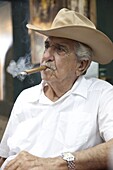 Cuban emigre smoking cigar wearing a cowboy hat in Calle Ocho, Miami, Florida, United States of America, North America
