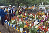 Mariachi group playing at a flower covered grave, Dia de Muertos (Day of the Dead) celebrations in a cemetery in Tzintzuntzan, Lago de Patzcuaro, Michoacan state, Mexico, North America