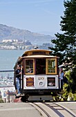 One of the famous cable cars on the Powell-Hyde track, with the island prison of Alcatraz in the background, San Francisco, California, United States of America, North America