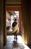 Local man in national dress backlit by evening sunlight at the Jakar Dzong, Jakar, Bumthang, Bhutan, Asia