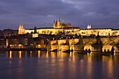 St. Vitus Cathedral, Charles Bridge and the Castle District illuminated at night in winter, seen from across the Vltava River, Prague, Czech Republic, Europe