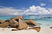 Granite boulders on the shore at Anse Lazio, island of Aride visible on horizon, Baie Sainte Anne district, Island of Praslin, Seychelles, Indian Ocean, Africa