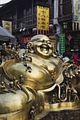 A golden statue of a reclining laughing Buddha covered in small Buddhas, Qinghefang Old Street in Wushan district of Hangzhou, Zhejiang Province, China, Asia