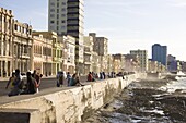 View along The Malecon showing people sitting on the seawall enjoying the evening sunshine, Havana, Cuba, West Indies, Central America