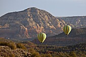 Two hot-air balloons flying low among red rock formations, Coconino National Forest, Arizona, United States of America, North America