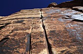 A rock climber tackles an overhanging crack in a sandstone wall on the cliffs of Indian Creek, a famous rock climbing area in Canyonlands National Park, near Moab, Utah, United States of America, North America