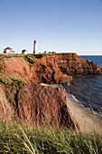 Lighthouse on a cliff overlooking a sandy beach on Havre-Aubert Island in the Iles de la Madeleine (Magdalen Islands), Quebec, Canada, North America