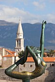 Statue of naked dancing girl on a rock with Budva old town in the background, Budva, Montenegro, Europe