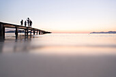 Familie mit zwei kleinen Kindern im Mallorca Urlaub stehen auf einem Steg in der Morgenstimmung. Strand Playa de Muro, Alcudia, Mallorca, Balearen, Spanien