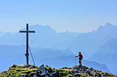 Frau beim Wandern geht auf Gipfelkreuz des Zennokopf zu, Watzmann im Hintergrund, Zennokopf, Chiemgauer Alpen, Oberbayern, Bayern, Deutschland