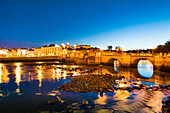 View across Rio Gilao towards old town and roman bridge at twilight, Tavira, Algarve, Portugal