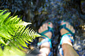 Woman stands in a spring creek during summer in Montana wearing sandals