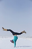 Girl does handstand in the snow of Roy, New Mexico
