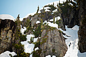 Two backpackers climb a snow filled gully high in the mountains of British Columbia, Canada.