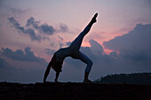 Mädchen macht Yoga bei Sonnenuntergang am Strand in Sri Lanka