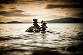 Two small rock stacks are slowly covered by water as the tide rises near Sechelt, BC, Canada.