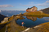 A male hiker at the lake of the beautiful located Sudetendeutsche mountain hut during the Glocknerrunde, a 7 stage trekking from Kaprun to Kals around the Grossglockner, the highest mountain of Austria.     Located in the heart of the Hohe Tauern National