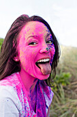 Caucasian woman splattered with paint powder with tongue out
