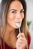 Smiling Caucasian woman licking spoon