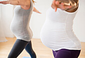 Pregnant women practicing yoga with arms outstretched