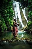 A waterfall on Tanna Island with a man in traditional costume in the foreground, Tanna Island, Vanuatu