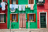 Laundry hangs in front of a row of colourful houses, Burano, Venice, Italy