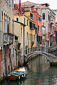 A small canal with a boat and bridge, Venice, Italy