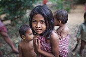 Young girl carries her brother in a krawma, Mondulkiri, Cambodia