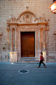 Girl Passing In Front Of Esglesia Del Roser, A Church In Ciutadella, Menorca, Balearic Islands, Spain