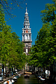 People in small boat going along small canal with spire of the Zuiderkerk church behind, Amsterdam, Holland
