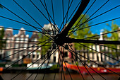 Silhouette of bicycle wheel in front of canal and traditional gabled houses, Amsterdam, Holland