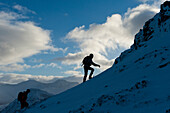 Walkers climbing the snowy slopes of Sgorr Dhearg near Glen Coe, Highlands, Scotland