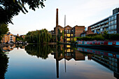 Flats and chimney reflected in the water of Regents Canal, London, UK