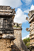 'Detailed stone carvings on ancient Mayan buildings with blue sky and clouds; Chichen Itza, Yucatan, Mexico'