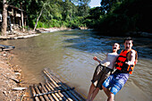 'Young tourists bamboo rafting down the river; Chiang Mai, Thailand'