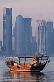 contrast between the traditional boats or qatari dhows at dock and the modern buildings in the skyline of the west bay city center including burj doha built by the french architect jean nouvel, doha, qatar, persian gulf, middle east