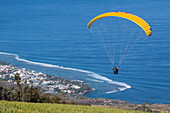 paraglider taking off from the runway on the heights of saint-leu, reunion island, indian ocean, france
