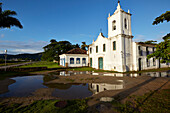 Morning sun, potholes, in the rain filled Rua Fresca, church Iglesia de Nostra Senora das Dores, historic old town, Paraty, Costa Verde, Rio de Janeiro, Brazil