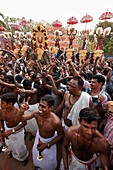 Musicians with wind and percussion instruments playing deafening loud, men dancing around them, decorated elephants and illuminated timber scaffolding Aana Pandal, Nemmara Vela, Vela Festival takes place in summer after harvest, Hindu temple festival in t