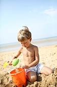 Little boy at the beach playing in the sand