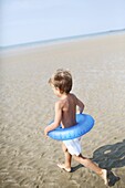 Little boy at the beach with his rubber ring